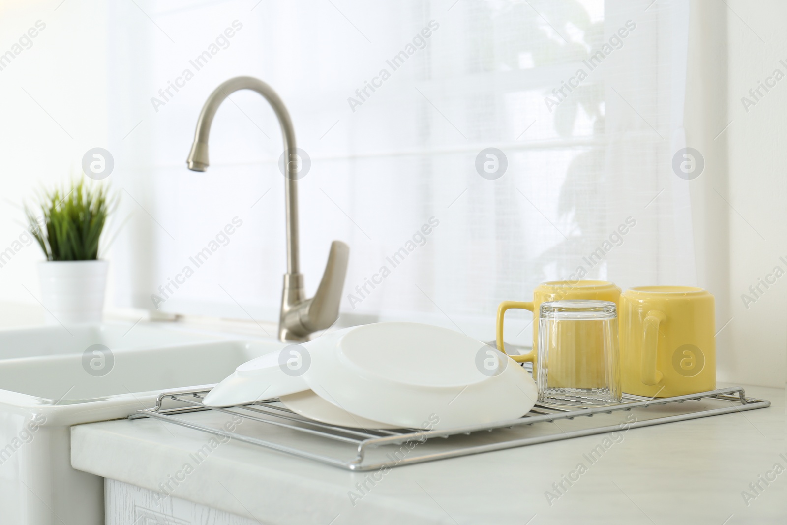 Photo of Clean dishes drying on rack in modern kitchen