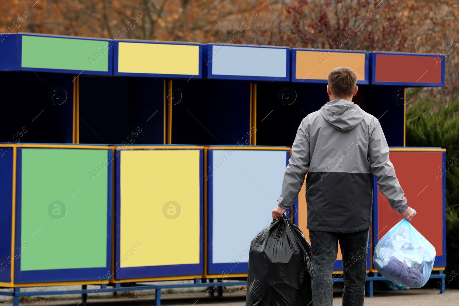 Photo of Man with garbage at recycling point outdoors, back view