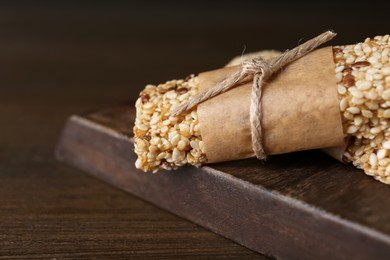 Photo of Tasty sesame seed bars on wooden table, closeup. Space for text