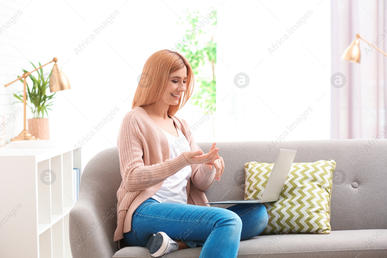 Photo of Woman using laptop for video chat in living room