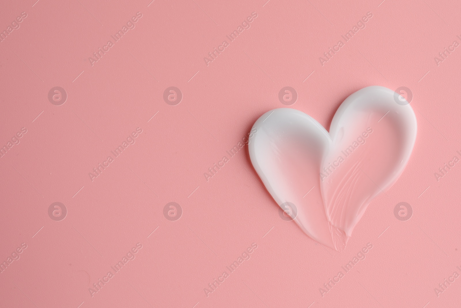 Photo of Sample facial cream on pale pink background, top view. Space for text