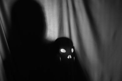Photo of Silhouette of creepy ghost with skull behind grey cloth, space for text