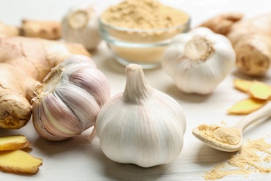 Photo of Ginger and fresh garlic on white table, closeup. Natural cold remedies