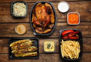 Photo of Plastic containers with different dishes on wooden table, flat lay. Food delivery service