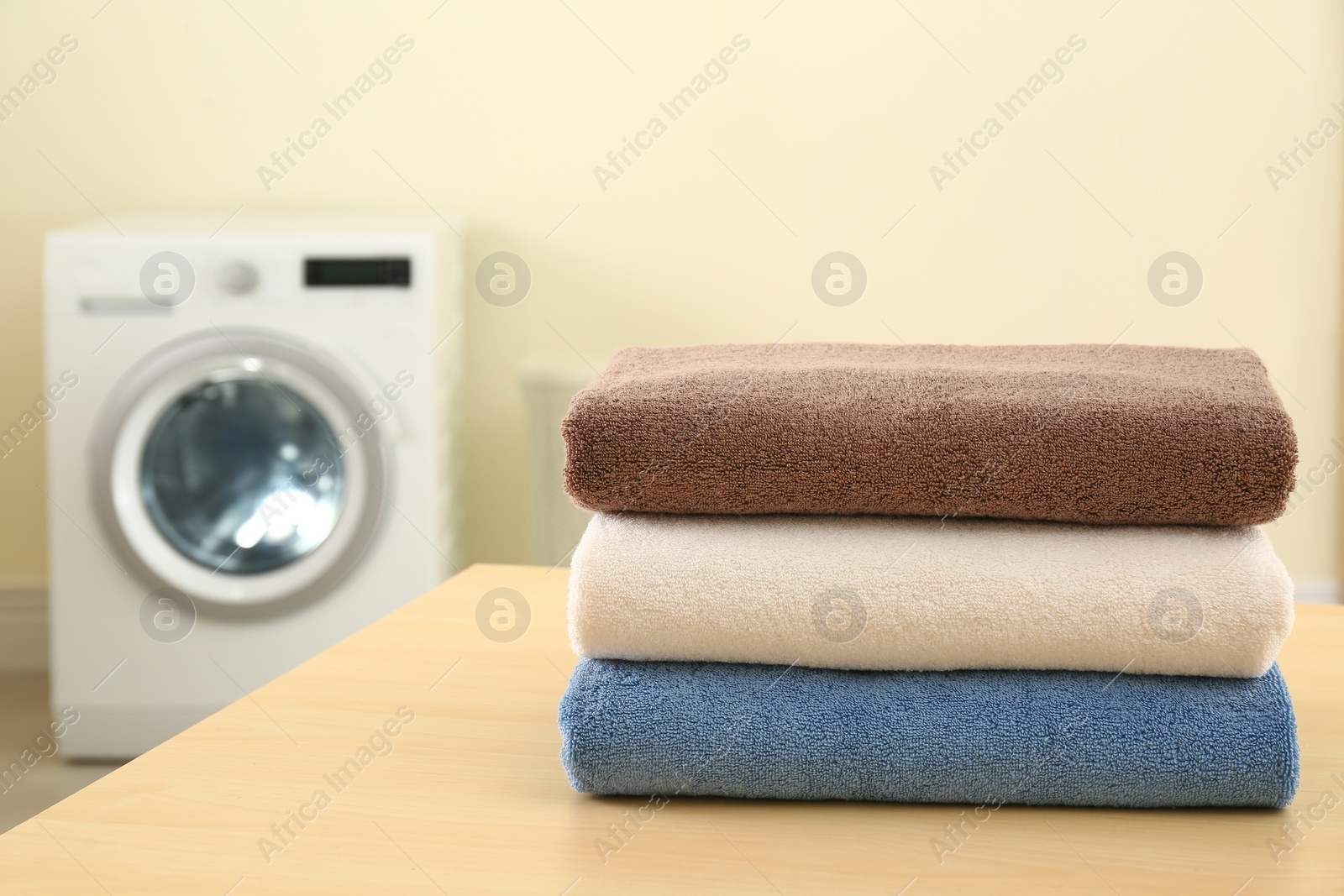 Photo of Stack of clean towels on table in laundry room. Space for text