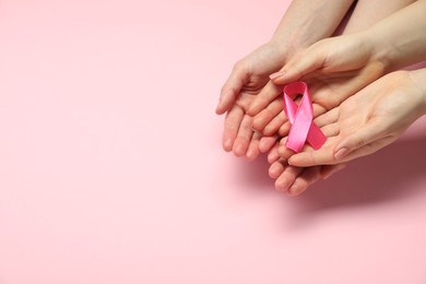 Photo of Breast cancer awareness. Women holding pink ribbon on color background, top view. Space for text