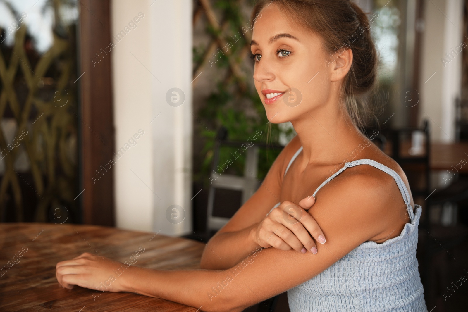 Photo of Beautiful young woman sitting on indoor terrace in cafe, space for text