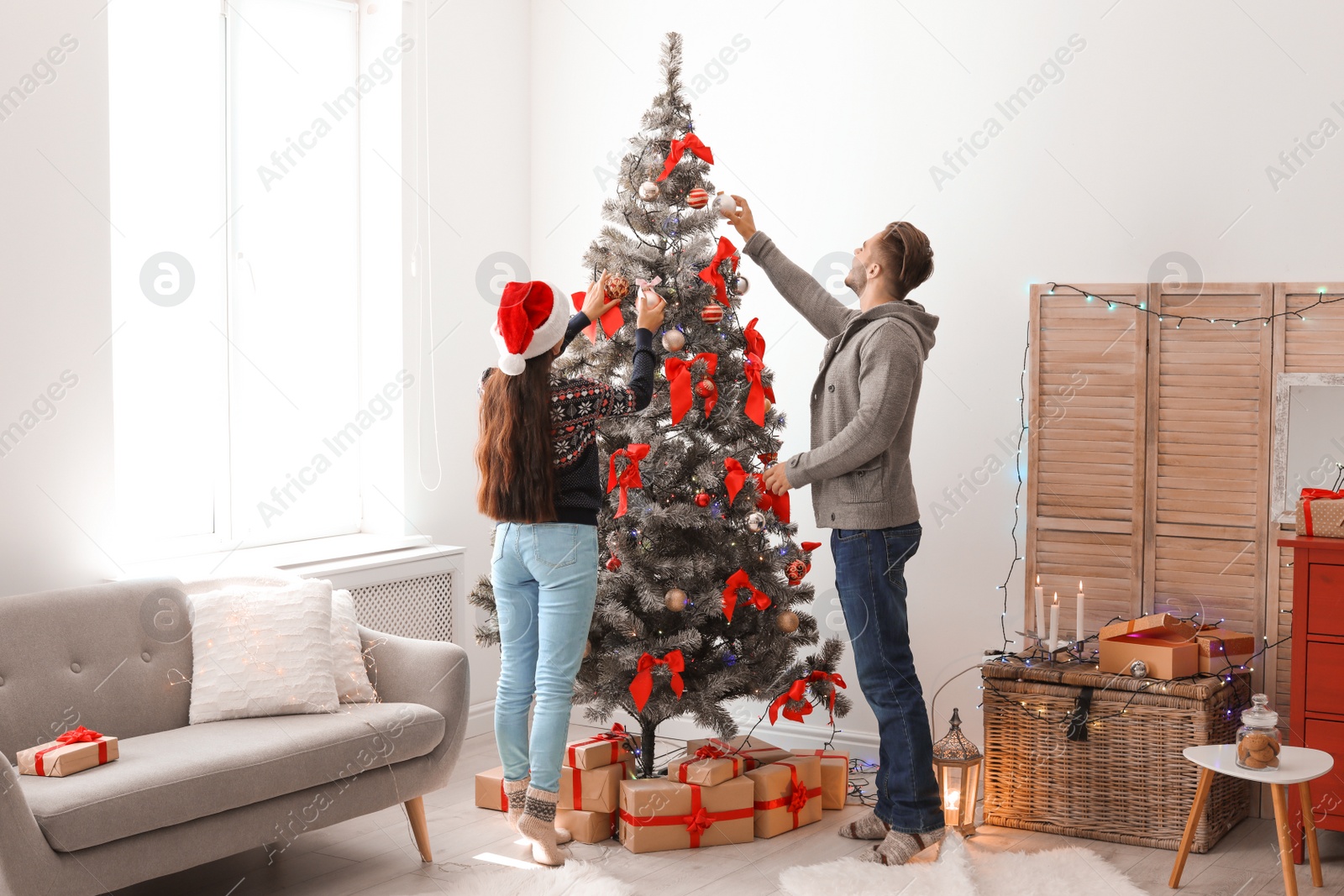 Photo of Happy young couple decorating Christmas tree together at home