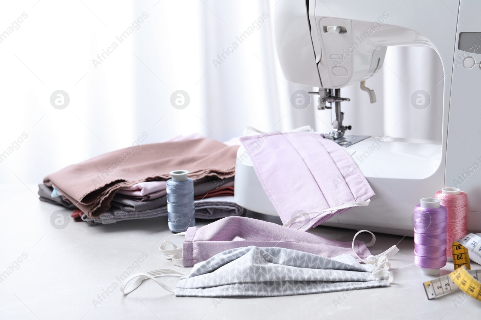 Photo of Sewing machine, homemade protective masks and craft accessories on table