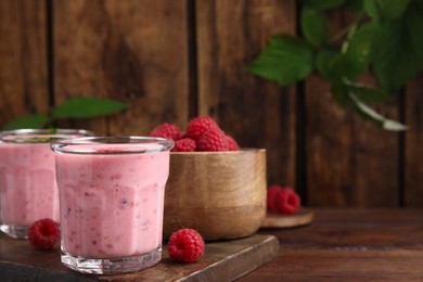 Tasty raspberry smoothie on wooden table, space for text