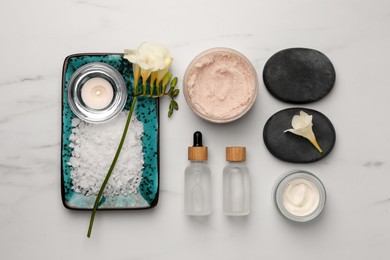 Flat lay composition with different spa products and flowers on white marble table