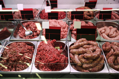Fresh raw ground meat and sausages in refrigerator at wholesale market