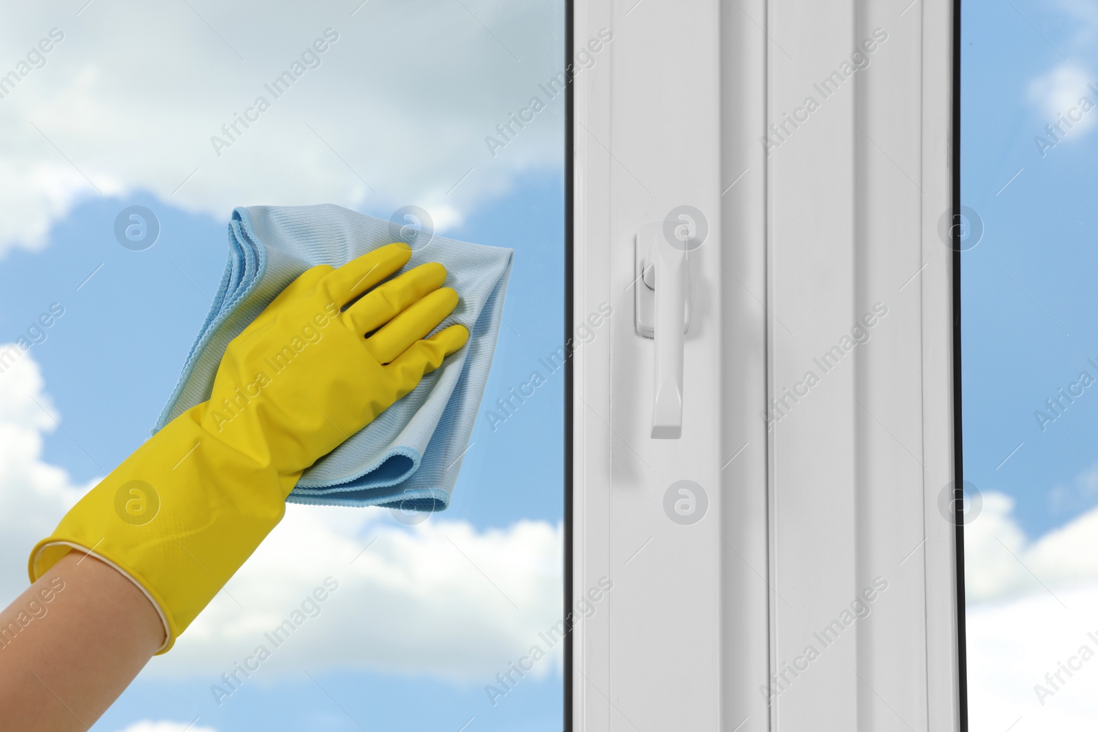 Photo of Woman cleaning window glass with rag indoors, closeup