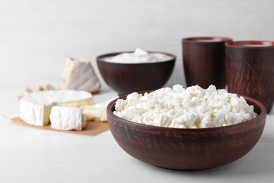 Photo of Clay brown bowl with cottage cheese on white wooden table, space for text