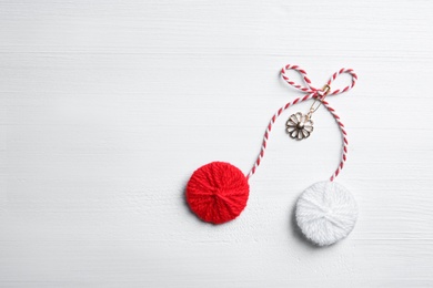 Traditional martisor on white wooden background, top view with space for text. Beginning of spring celebration