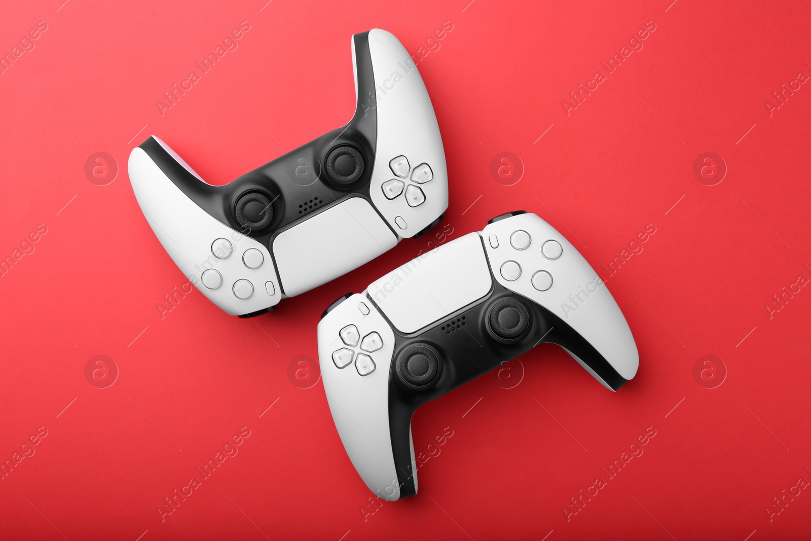 Photo of Wireless game controllers on red background, flat lay