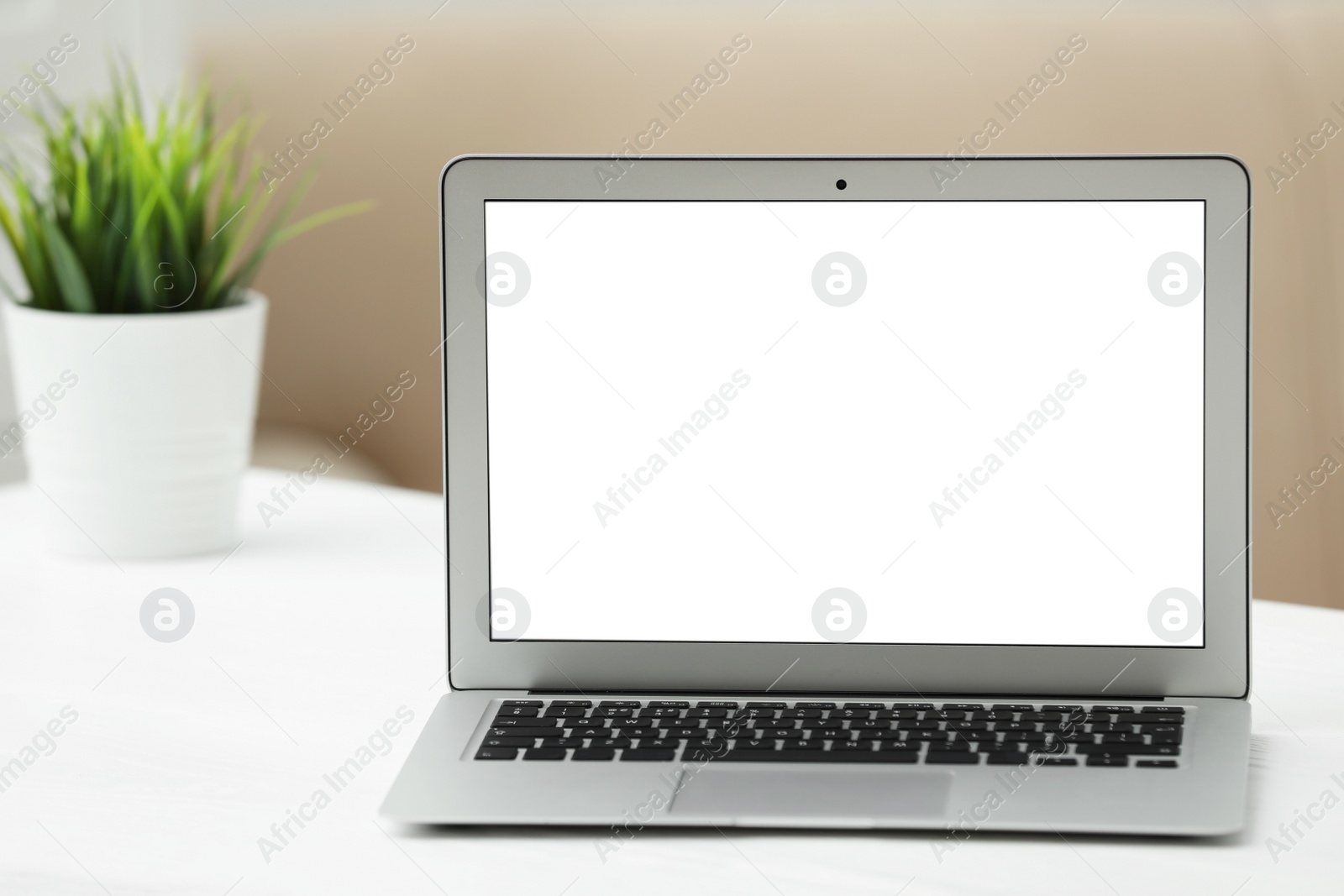 Photo of Laptop with blank screen on table indoors. Space for text