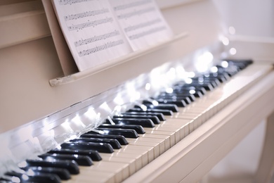 Glowing fairy lights on piano keys, closeup. Christmas music