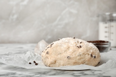 Photo of Raw wheat dough with chocolate chips on table