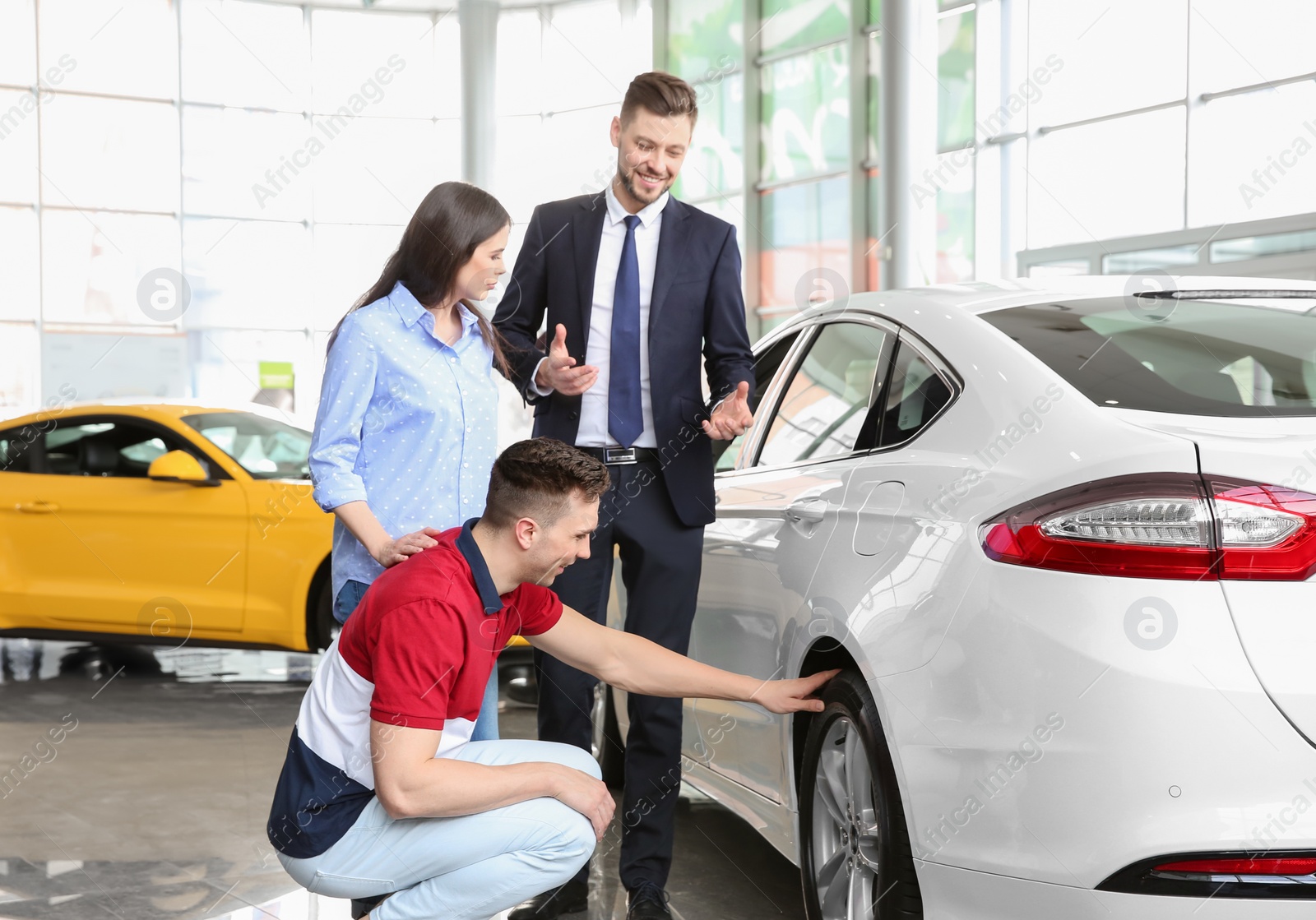 Photo of Young couple buying new car in salon