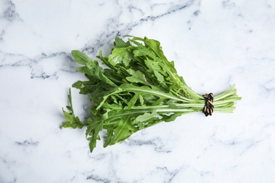 Fresh arugula on white marble table, top view