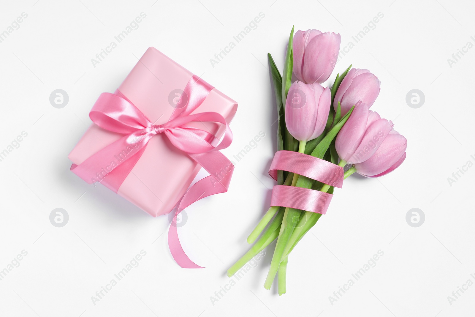 Photo of Beautiful gift box with pink bow and tulips on white background, flat lay