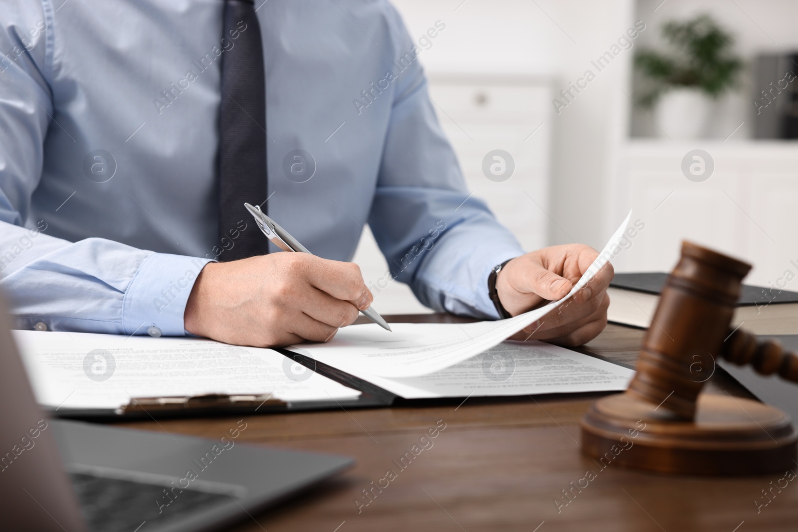 Photo of Lawyer working with documents at wooden table in office, closeup
