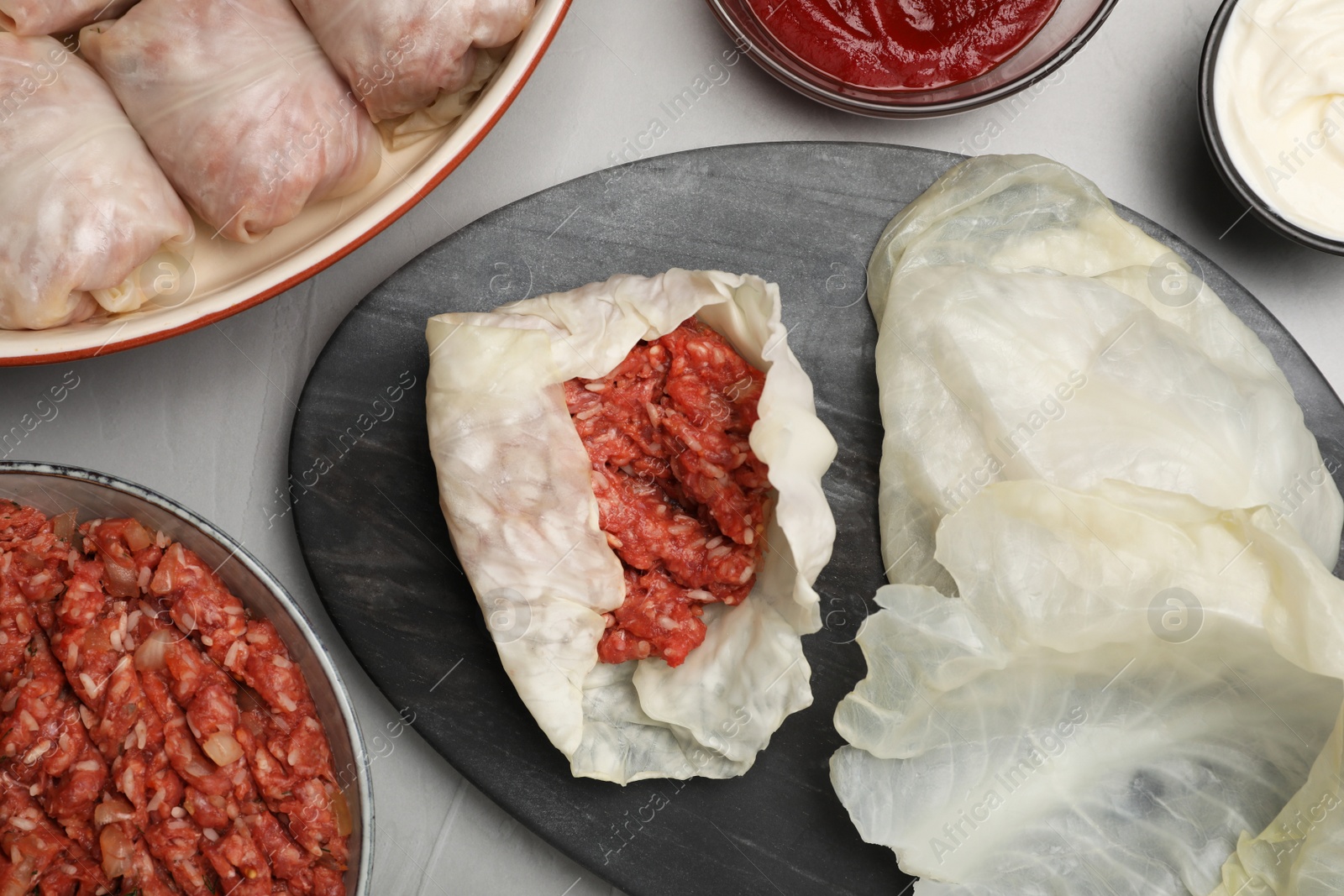 Photo of Preparing stuffed cabbage rolls on grey table, flat lay