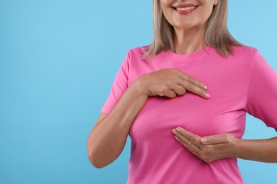 Photo of Woman doing breast self-examination on light blue background, closeup. Space for text