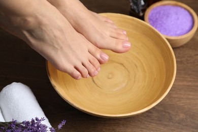 Photo of Woman soaking her feet in bowl with water, closeup. Pedicure procedure