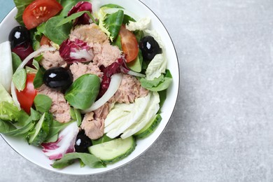 Photo of Bowl of delicious salad with canned tuna and vegetables on light grey table, top view. Space for text