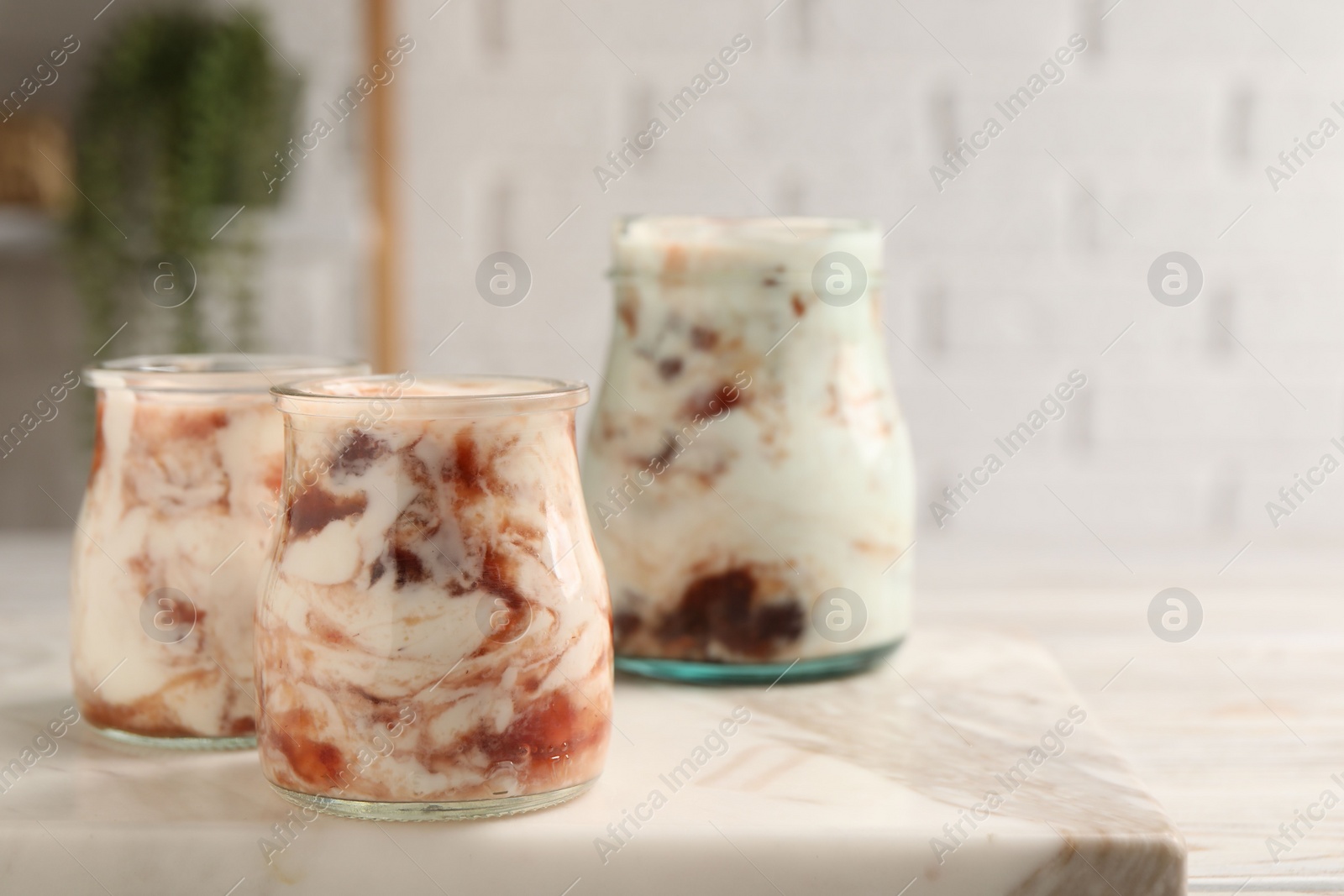 Photo of Tasty yoghurt with jam on white marble board, closeup. Space for text