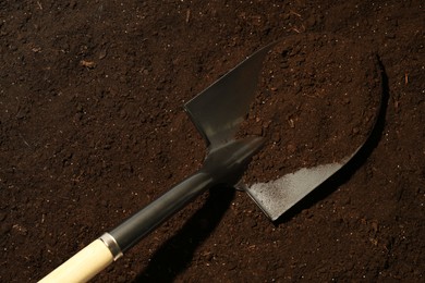 Photo of Metal shovel on fertile soil, top view. Gardening tool