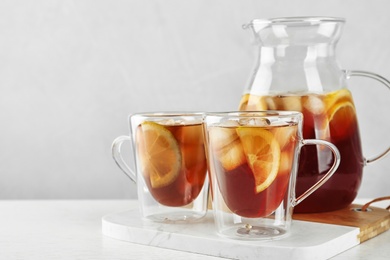 Photo of Cups and jug of refreshing iced tea on light table