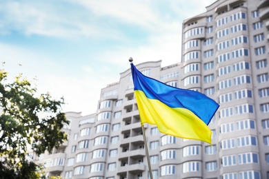 National flag of Ukraine fluttering near building on sunny day