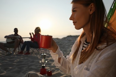 Photo of Friends resting on sandy beach. View from camping tent