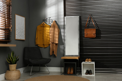 Photo of Hallway interior with modern furniture, mirror and hanging clothes