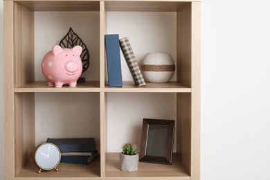 Shelving unit with decorative interior elements and piggy bank near white wall