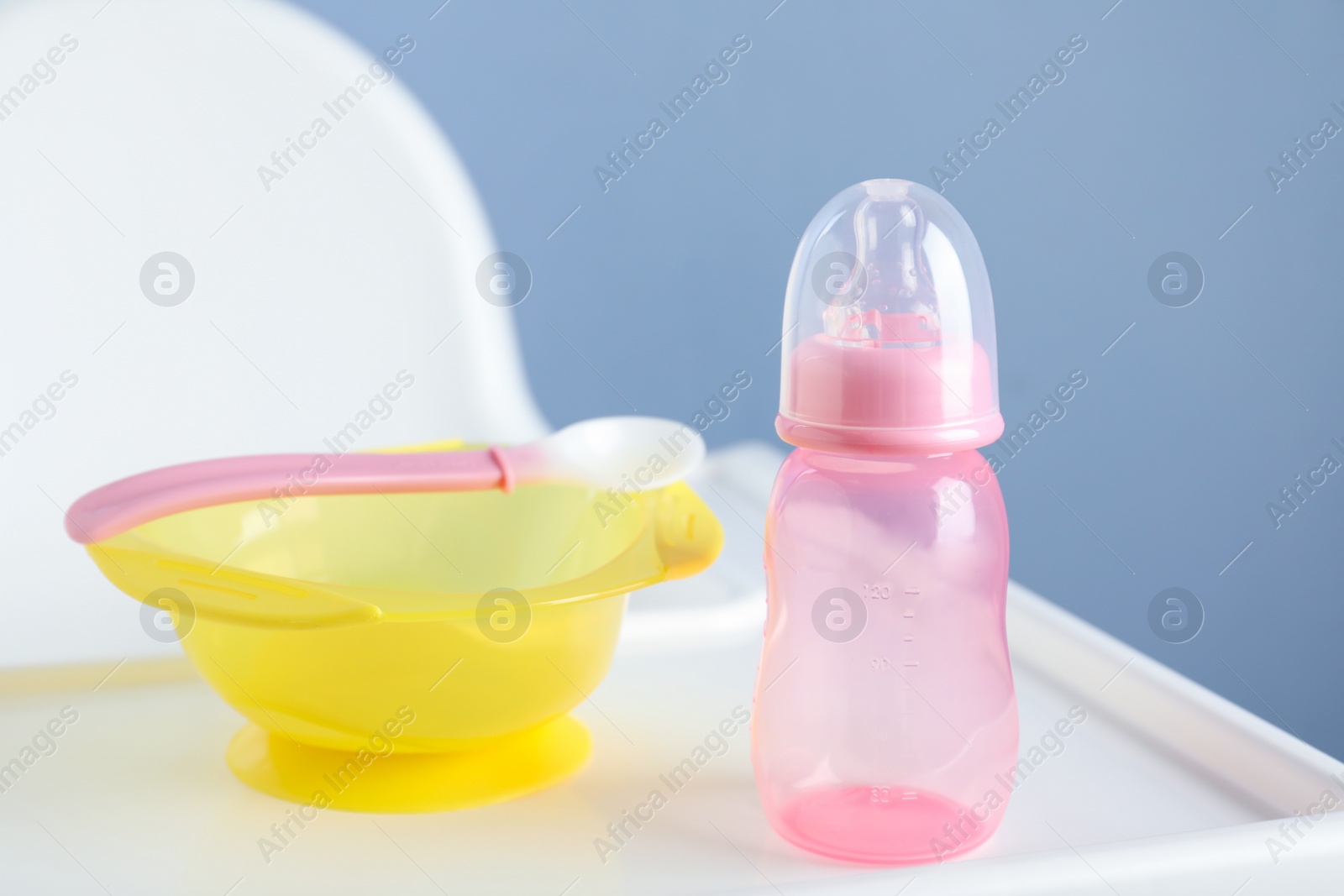 Photo of Set of plastic dishware on white feeding table. Serving baby food