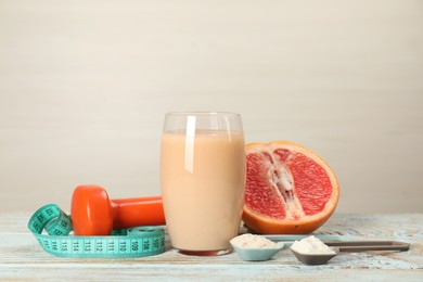 Photo of Tasty shake, grapefruit, dumbbell, scoops with different powders and measuring tape on wooden table against light background, space for text. Weight loss