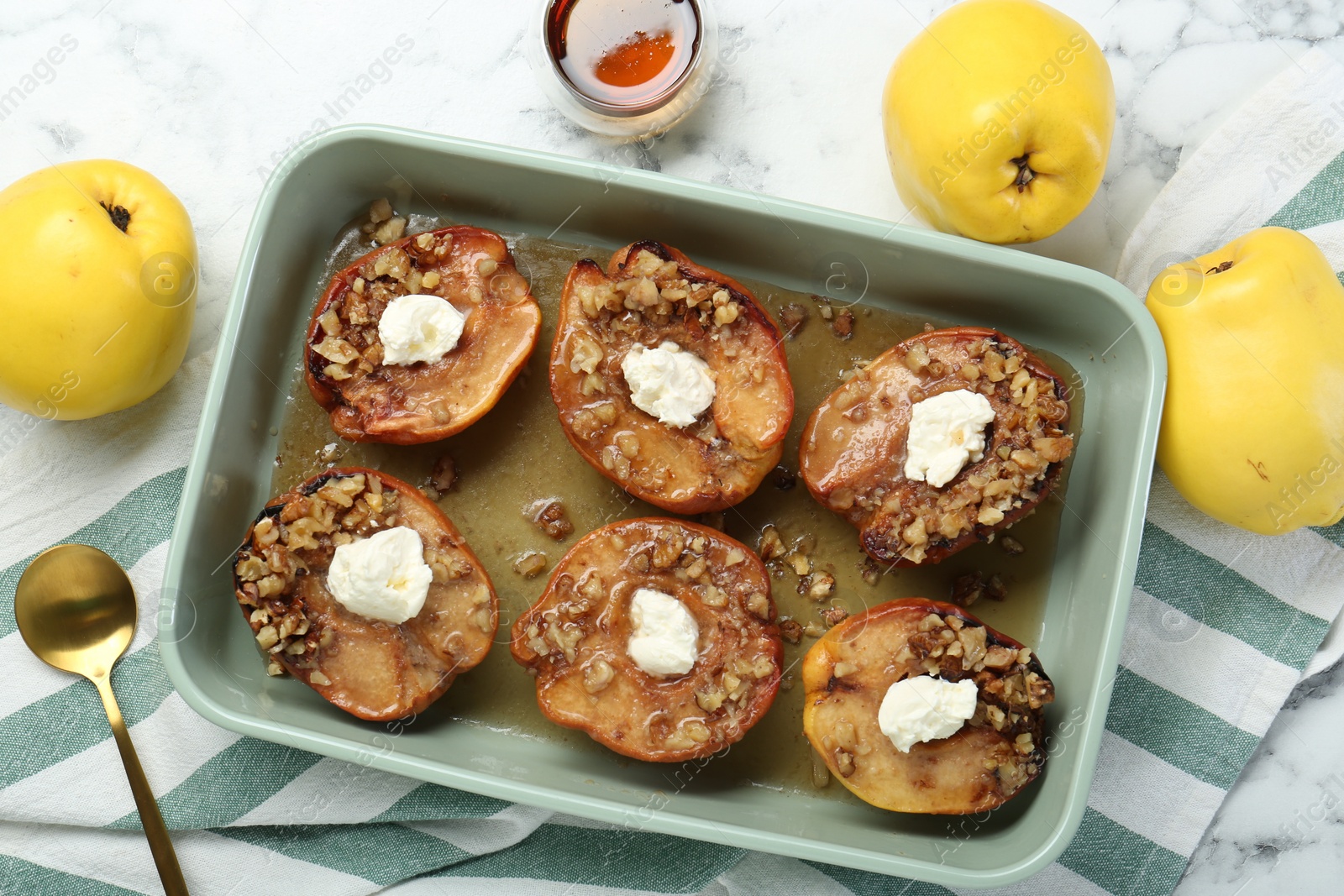 Photo of Tasty baked quinces with nuts, cream cheese and honey in dish on white marble table, flat lay