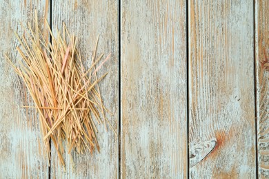 Heap of dried hay on light wooden background, flat lay. Space for text