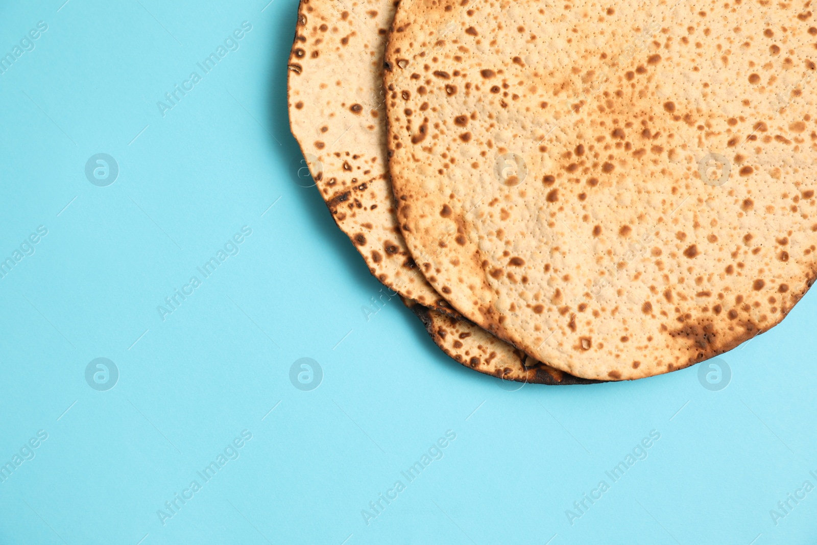 Photo of Tasty matzos on light blue background, flat lay with space for text. Passover (Pesach) celebration