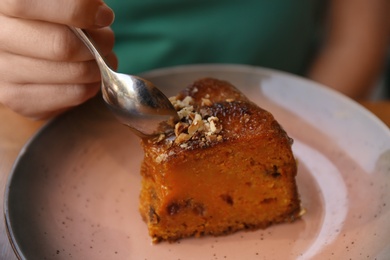 Photo of Woman eating slice of carrot cake at table, closeup