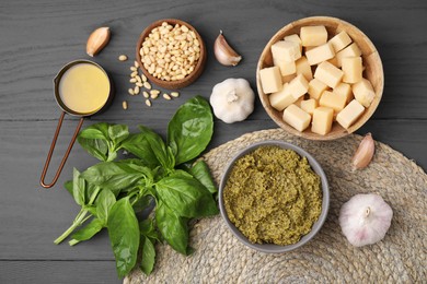 Photo of Tasty pesto sauce and ingredients on grey wooden table, flat lay