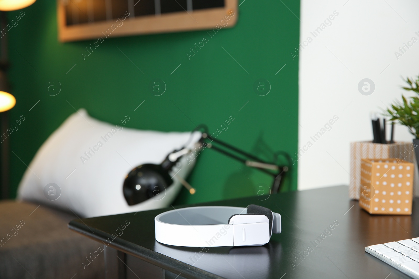 Photo of Stylish modern wireless headphones on table against blurred background, space for text