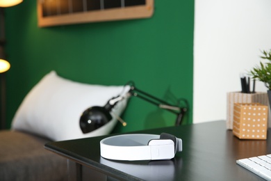 Photo of Stylish modern wireless headphones on table against blurred background, space for text