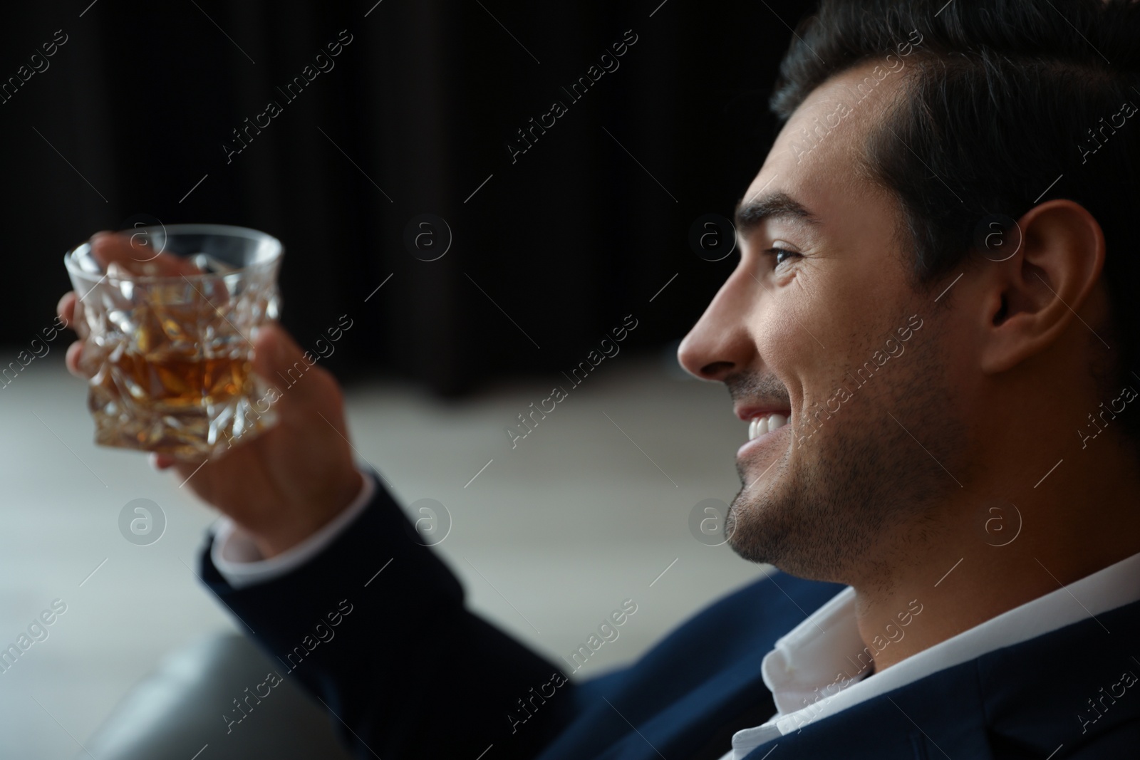 Photo of Young man with glass of whiskey indoors