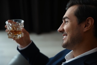 Young man with glass of whiskey indoors