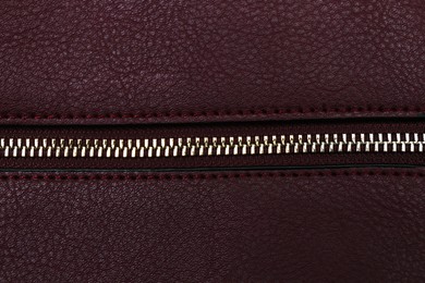 Photo of Burgundy leather fabric with zipper as background, top view